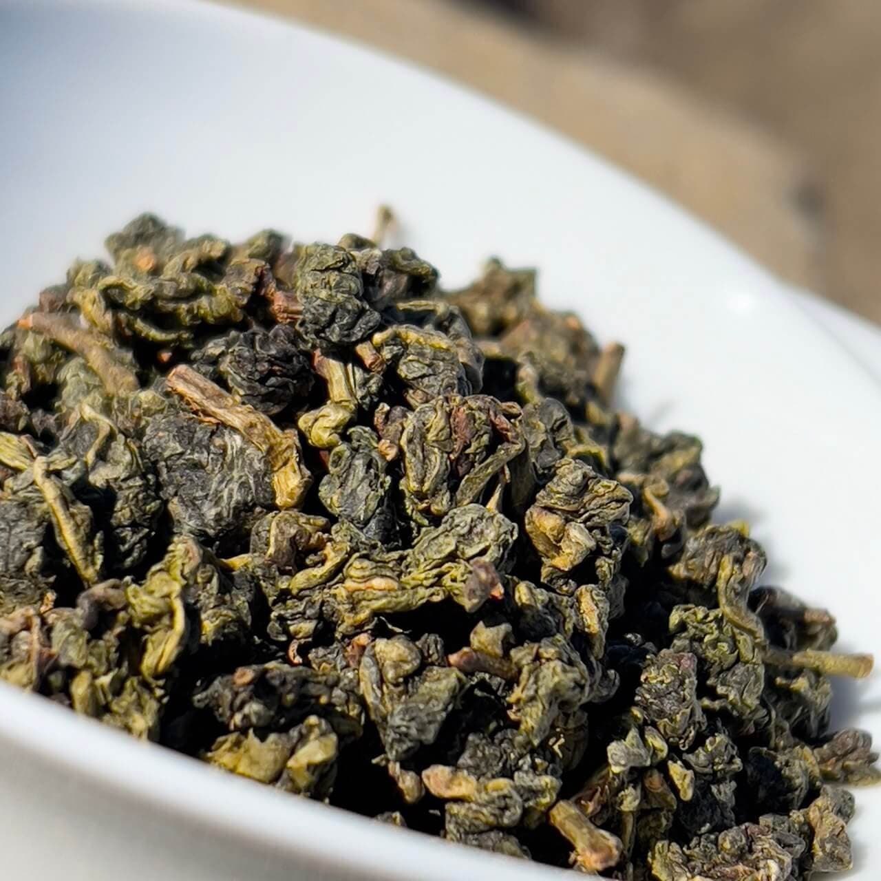 Tightly rolled green tea leaves in a white bowl